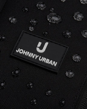 Nahe Nahaufnahme des schwarzen wasserabweisenden Sling Bags 'Charlie' von Johnny Urban mit sichtbaren Wassertropfen