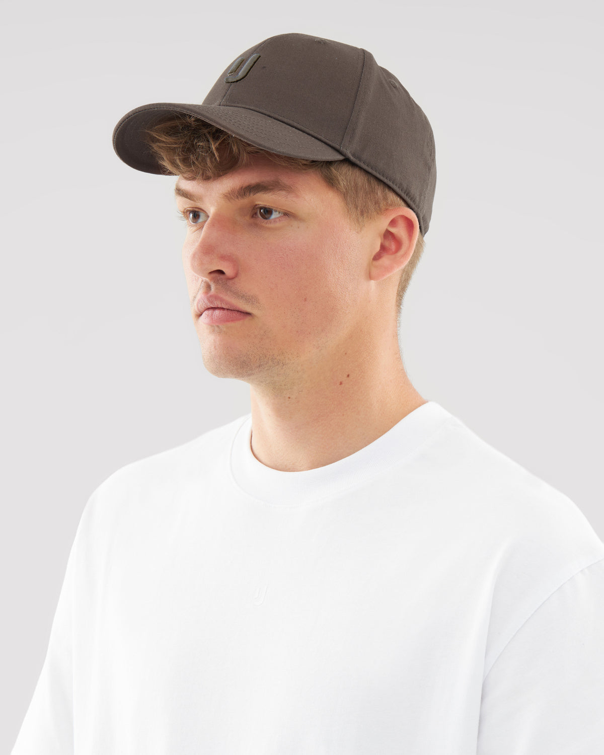 Mann trägt graue Johnny Urban Snapback-Cap 'Jason' und weißes T-Shirt, Blick nach links