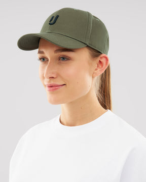 Frau trägt olivgrüne Snapback-Cap 'Jason' mit nahtlosem Visier und schwarzem 'J'-Logo