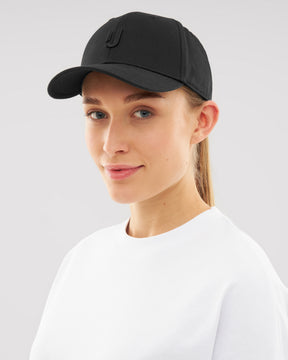 Frau trägt schwarzen Snapback Cap 'Jason' mit dezentem 'J'-Logo, weiße Shirt