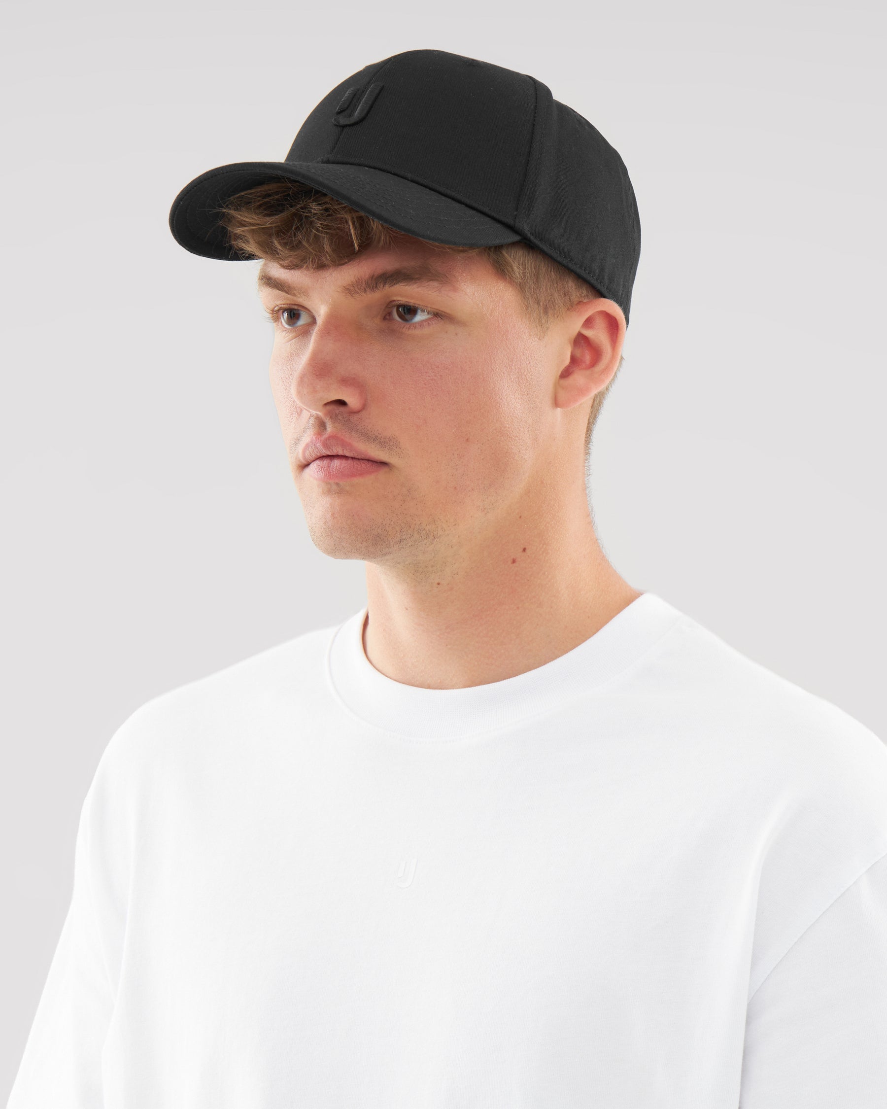 Mann mit schwarzer Johnny Urban Snapback Cap 'Jason' und weißem T-Shirt