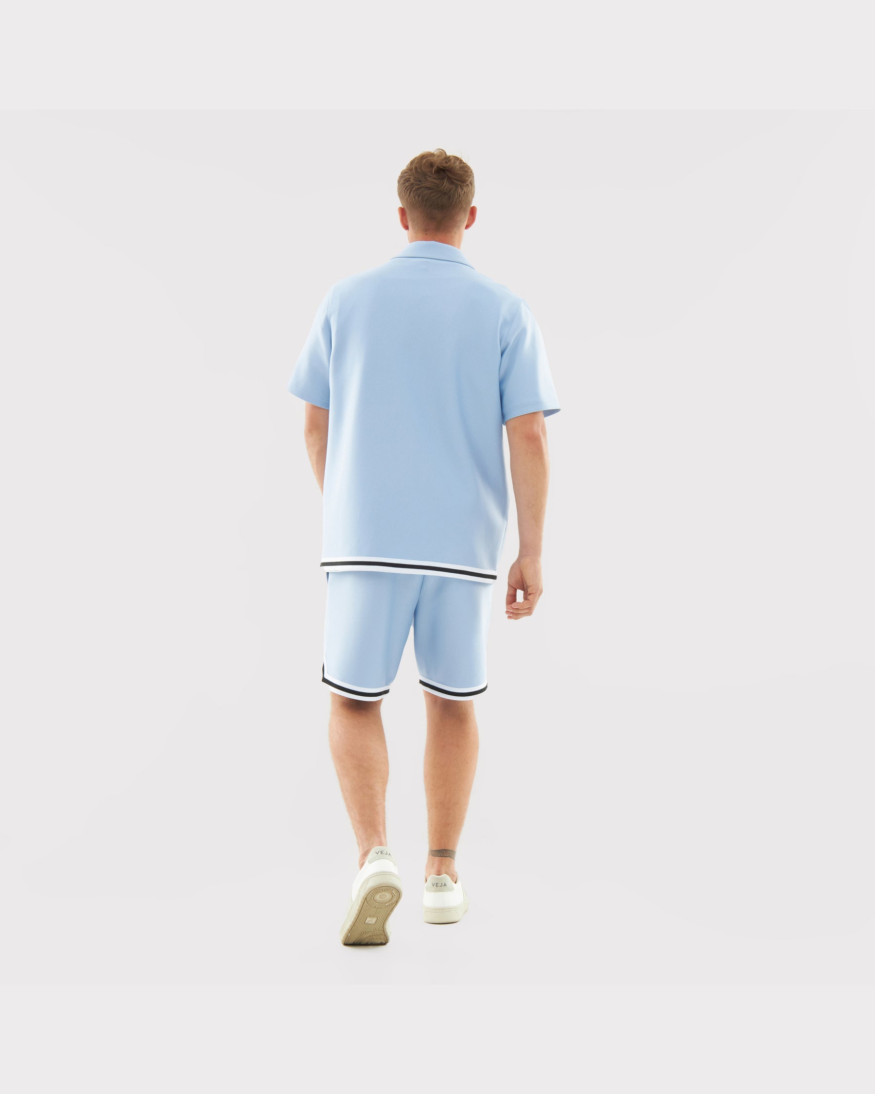 Mann von hinten in lockeren hellblauen Sommer-Shorts 'Parker' mit schwarz-weißen Saumstreifen