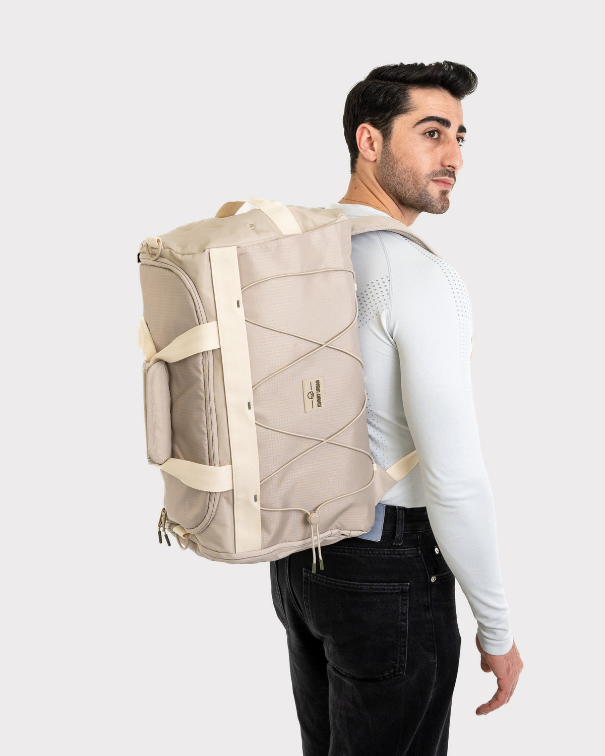 Beiger Duffle Bag 'Shawn Medium' von Johnny Urban, getragen von Mann mit weißem langärmligem Shirt und schwarzer Hose