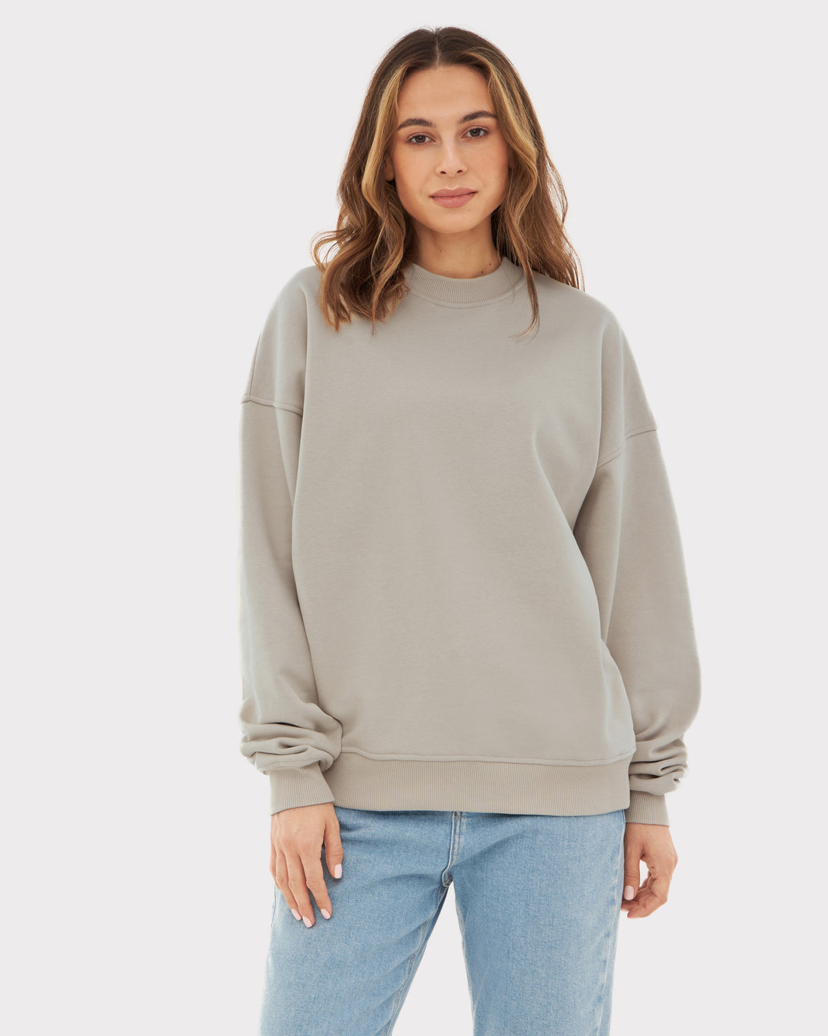 Frau trägt oversized beige Crewneck-Pullover ‚Carter‘ von Johnny Urban mit blauer Jeans