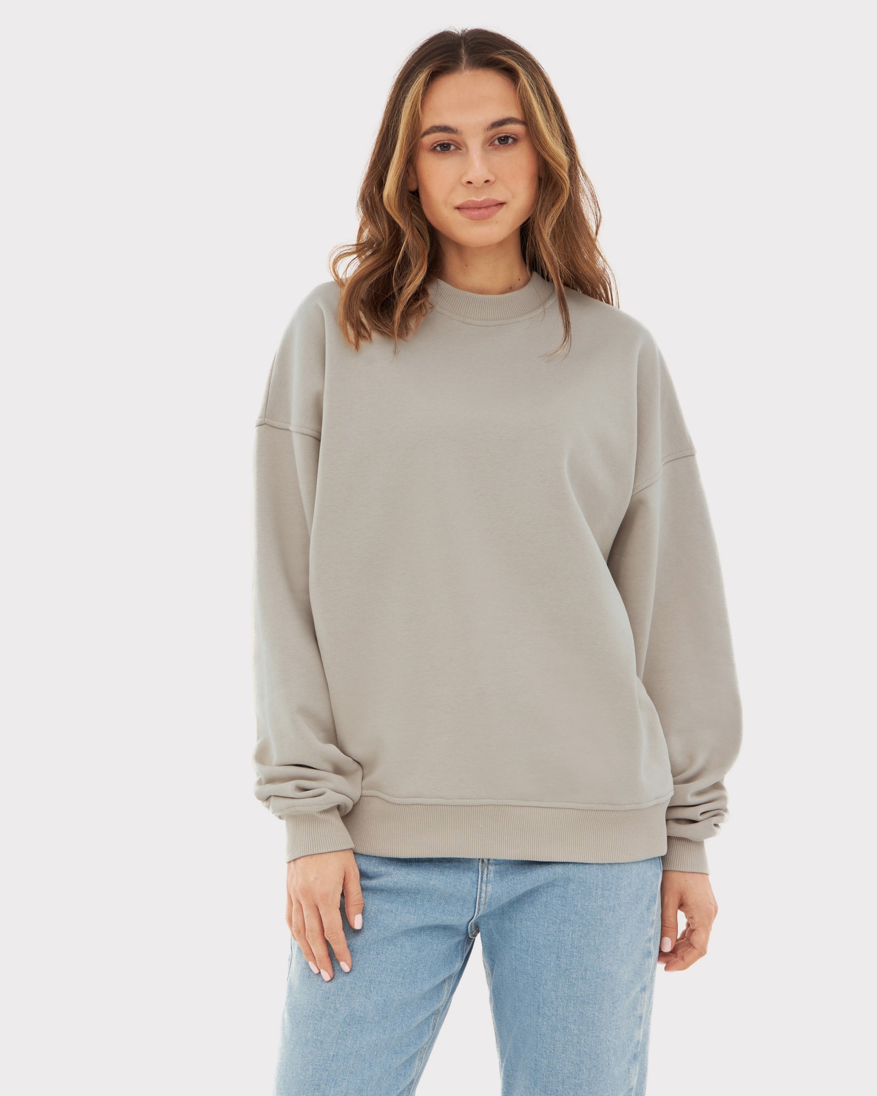 Frau trägt oversized beige Crewneck-Pullover ‚Carter‘ von Johnny Urban mit blauer Jeans