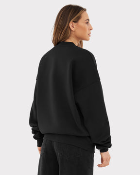 Dame von hinten mit oversized schwarzem Crewneck 'Carter' und schwarzen Jeans