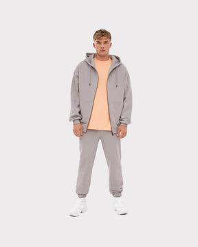 Mann trägt graue Jogginghose 'Owen', grauen Hoodie und helloranges T-Shirt