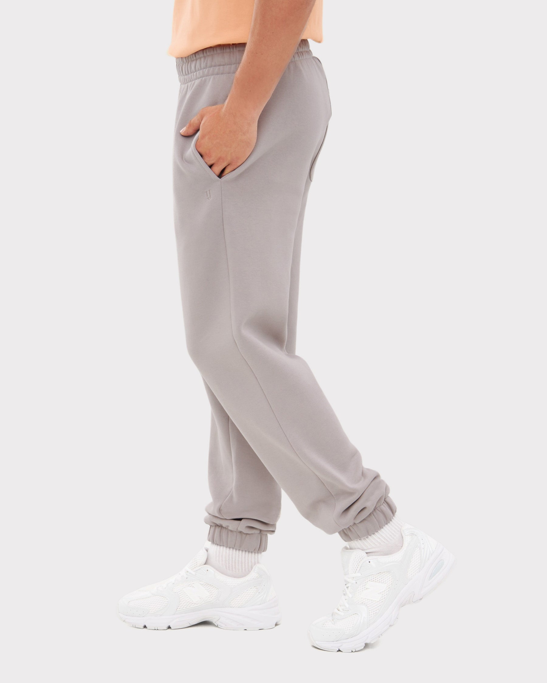 Seitliche Ansicht einer grauen Herren-Jogginghose 'Owen' mit elastischem Bund und Bündchen, getragen mit weißen Sportschuhen