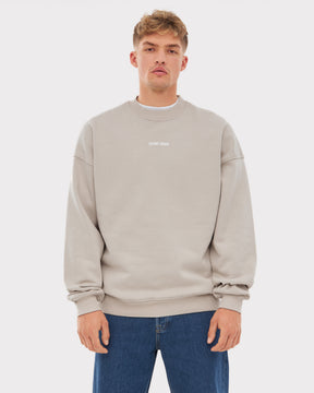 Mann trägt oversized Pullover 'Carter' von Johnny Urban in Beige mit kleinem Logo in der Mitte