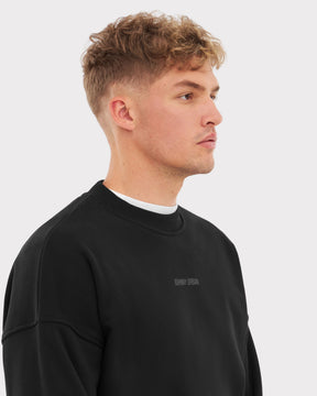 Mann trägt schwarzen Oversized Crewneck 'Carter' Sweatshirt mit kleinem 'Johnny Urban' Print vorne