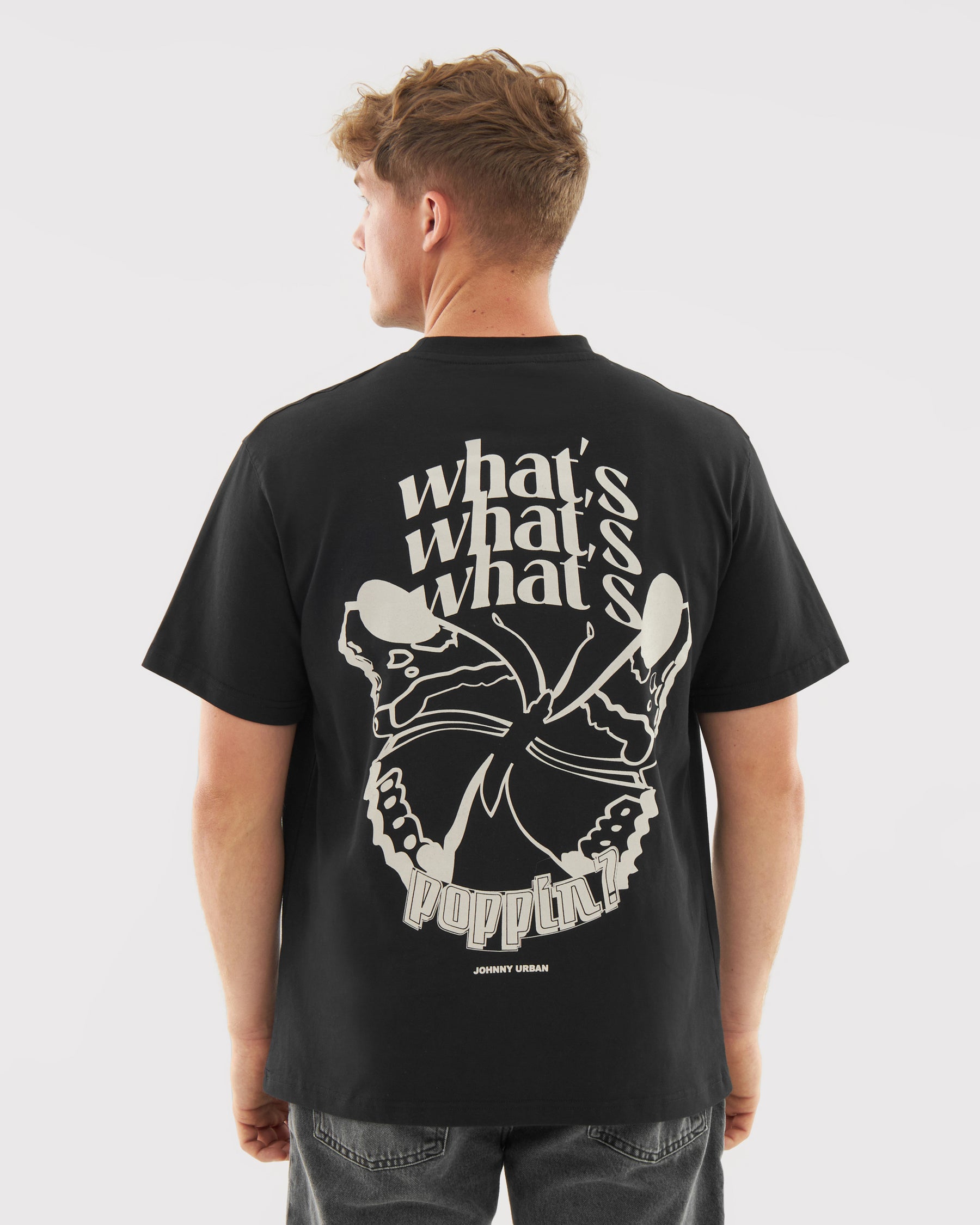 Mann trägt schwarzes T-Shirt 'Sammy Butterfly' mit großem hellen Schmetterlingsdruck und Text 'what's what's what's poppin?' auf dem Rücken