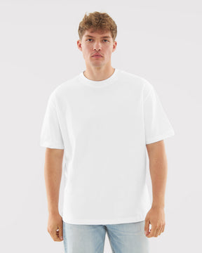 Mann mit neutralem Gesichtsausdruck trägt weißes T-Shirt "Sammy Butterfly" und helle Jeans