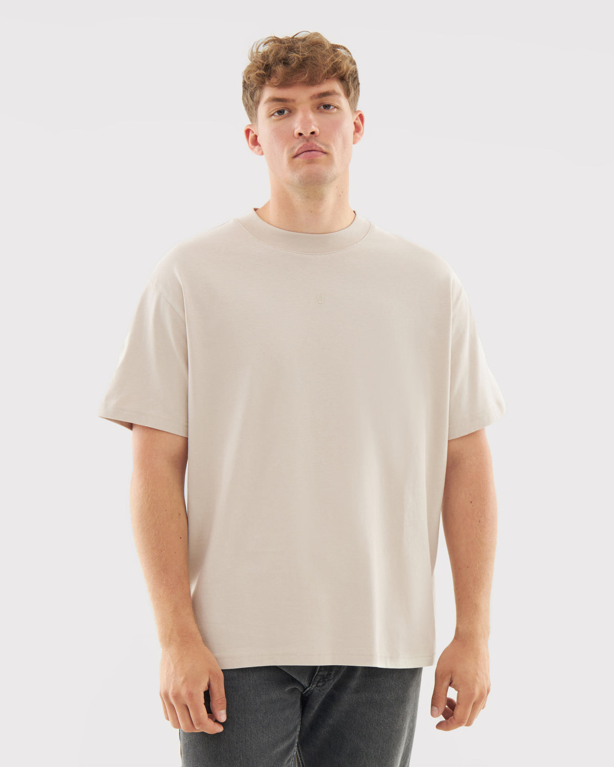 Mann trägt beige oversized T-Shirt 'Sammy Butterfly' und dunkle Jeans