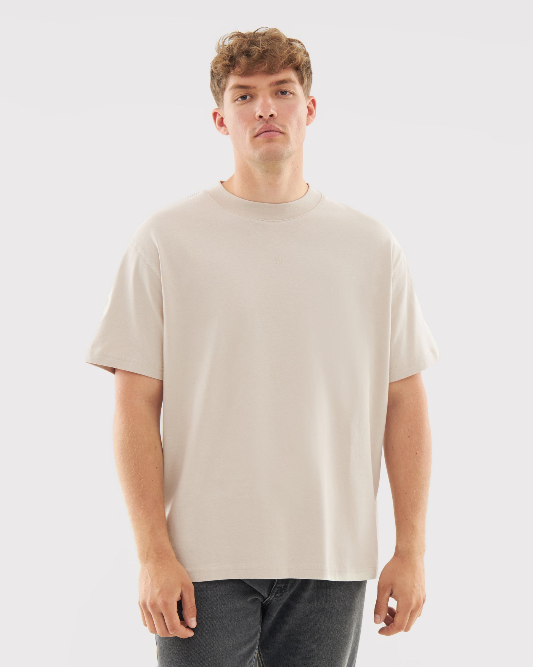 Mann trägt beige oversized T-Shirt 'Sammy Butterfly' und dunkle Jeans