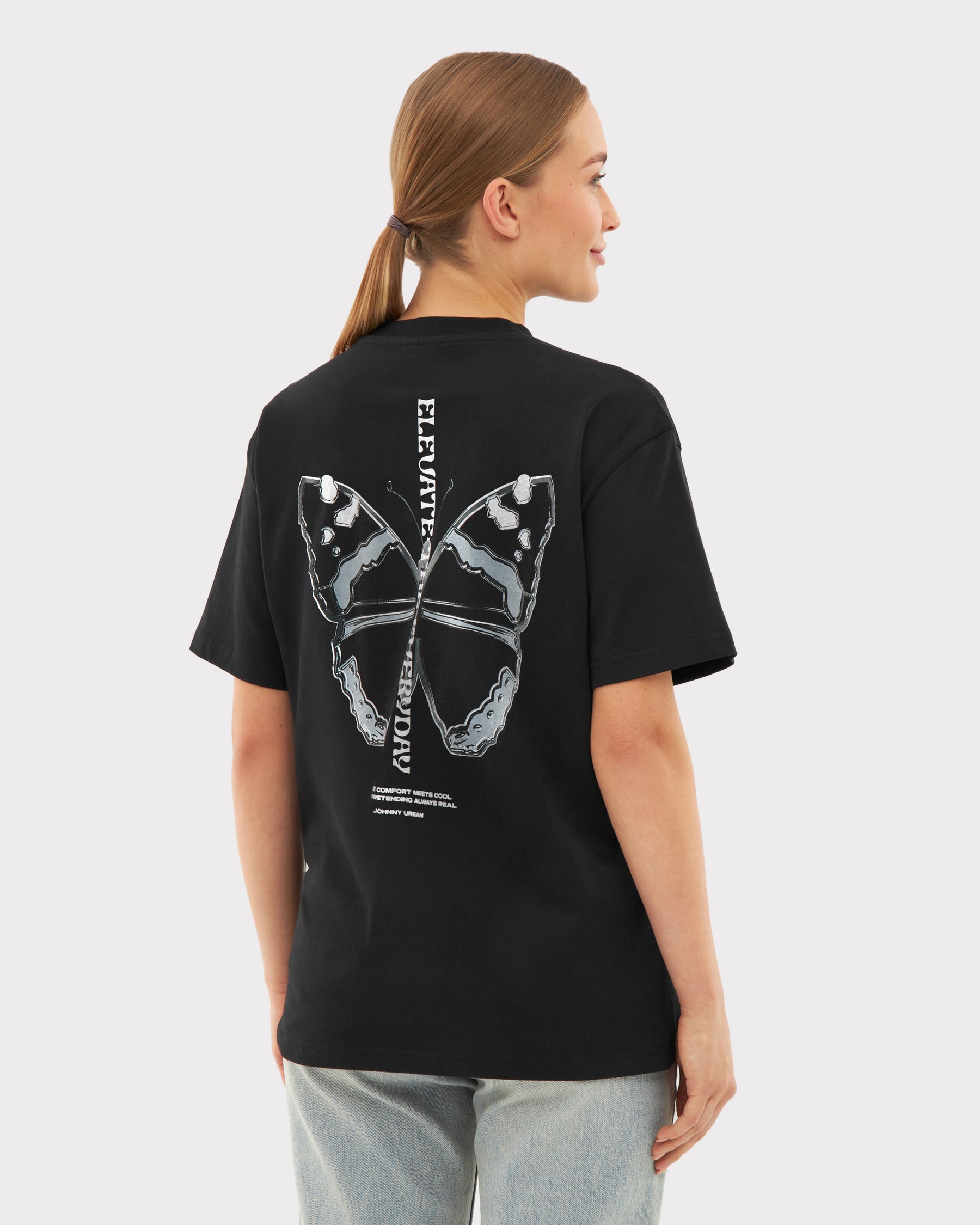 Frau trägt schwarzes Oversize-T-Shirt 'Sammy Chrome Butterfly' mit großem Schmetterlingsdruck hinten