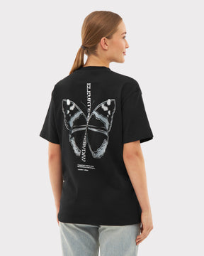 Frau trägt schwarzes Oversize-T-Shirt 'Sammy Chrome Butterfly' mit großem Schmetterlingsdruck hinten