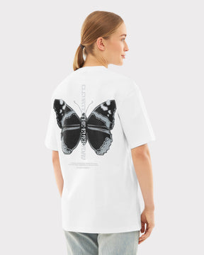 Frau mit Pferdeschwanz trägt weißes Oversize-T-Shirt 'Sammy Chrome Butterfly' mit großem schwarzem Schmetterlingsdruck auf dem Rücken