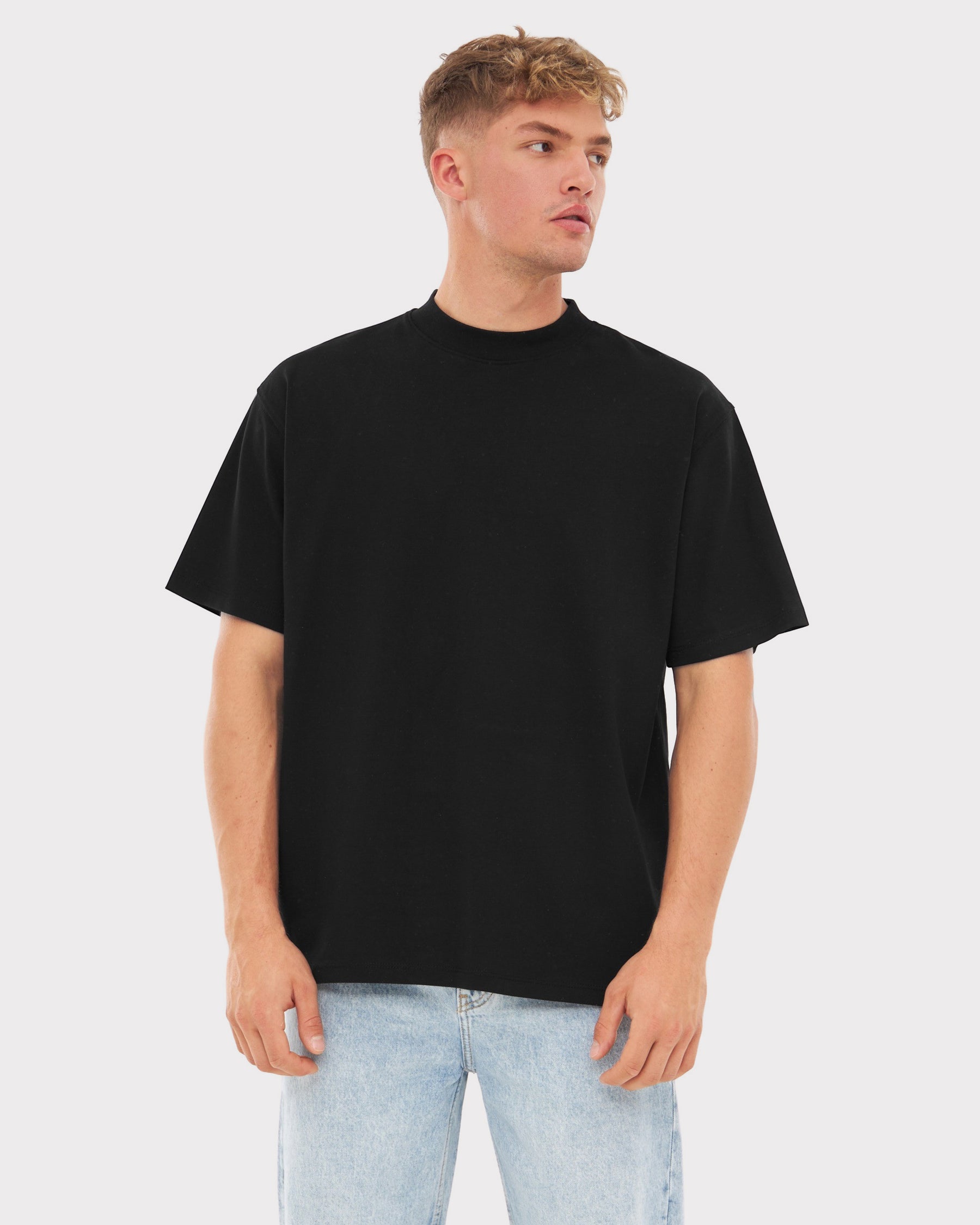 Mann trägt oversized schwarzes T-Shirt 'Sammy' und helle Jeans