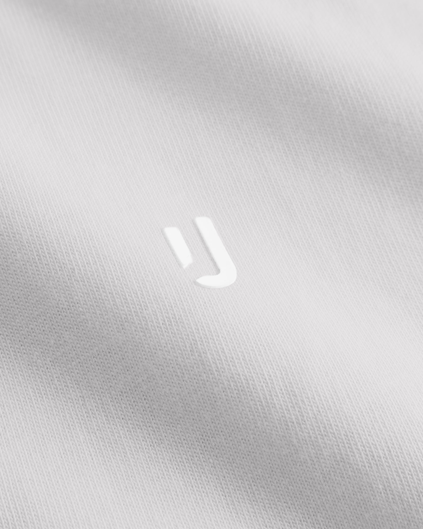Nahaufnahme des weißen Stoffs des T-Shirts 'Sammy Chrome Butterfly' mit geprägtem Johnny Urban Logo