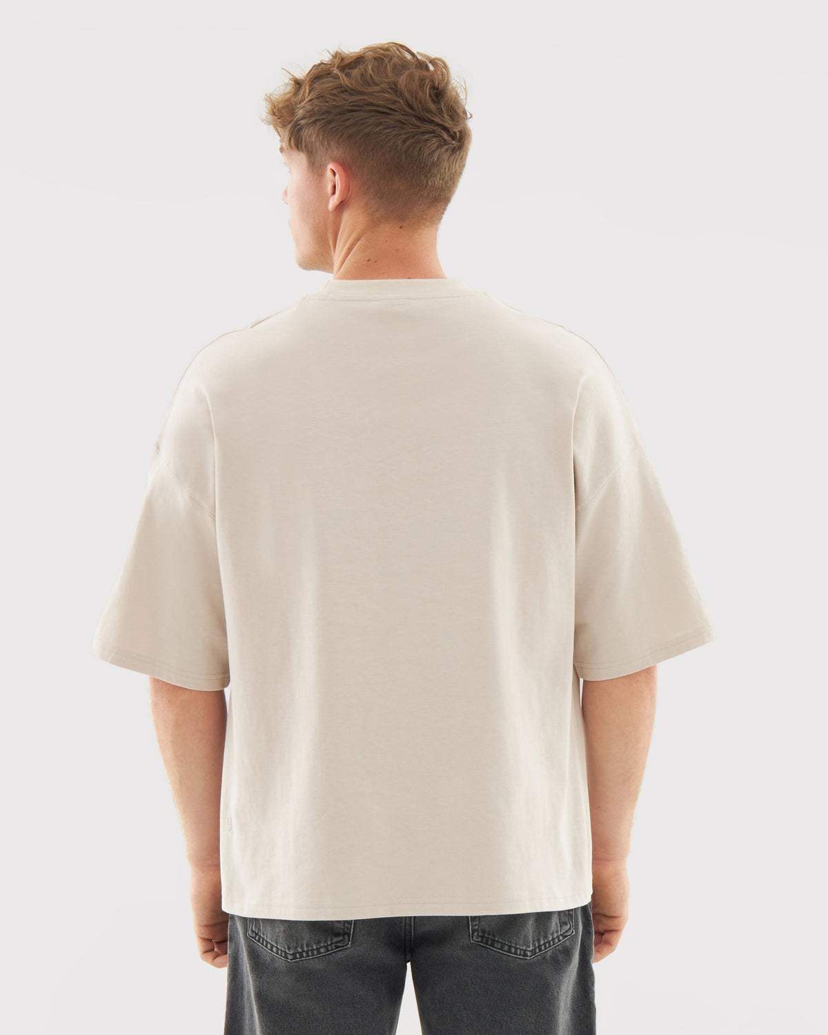 Mann von hinten trägt T-Shirt 'Vic' in Creme mit lockerem Schnitt und kurzen Ärmeln
