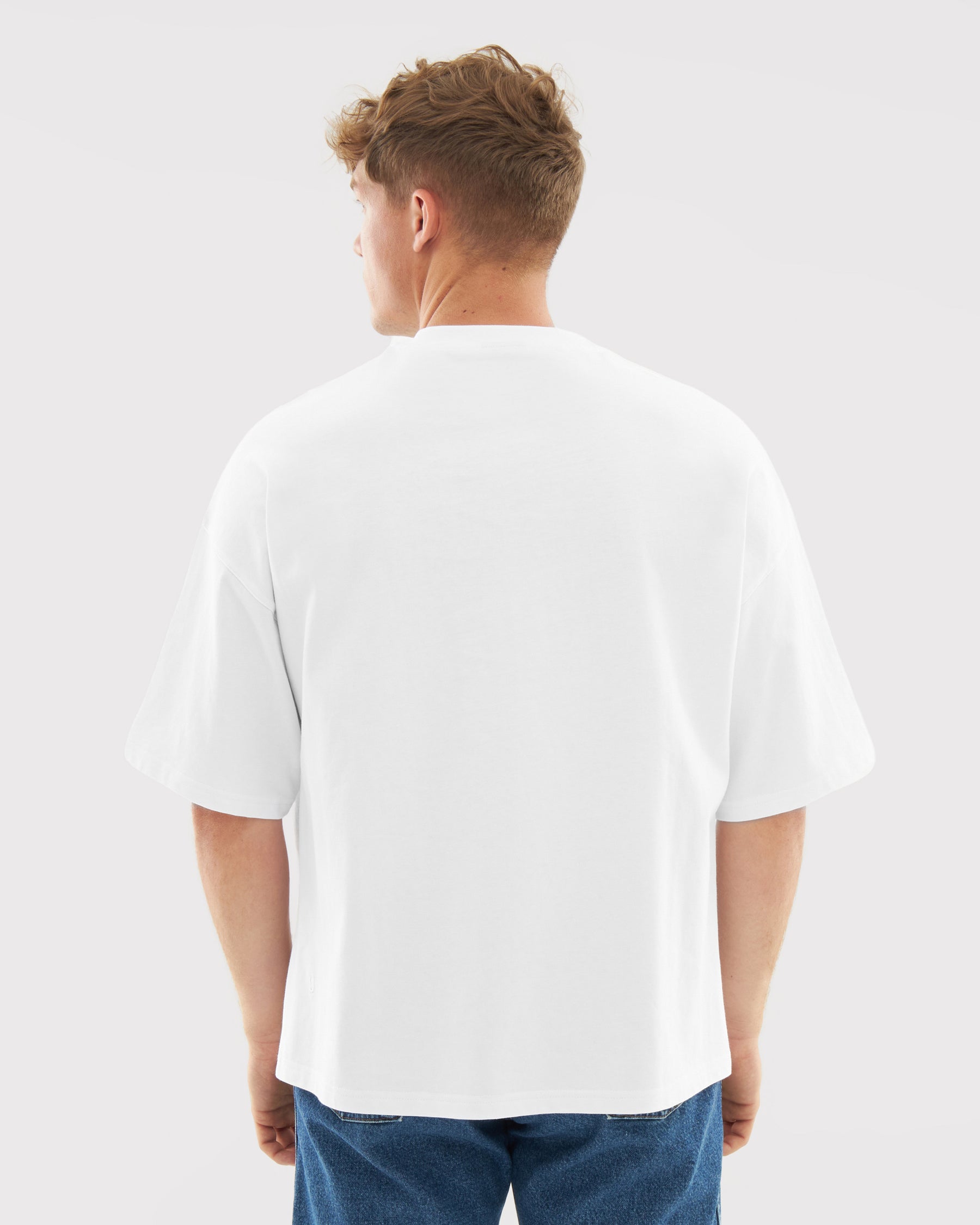 Mann trägt weißes, locker geschnittenes T-Shirt 'Vic' von hinten, kombiniert mit blauer Jeans