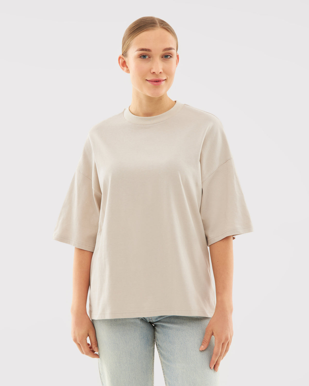 Beige T-Shirt 'Vic' mit kurzem, weitem Schnitt, getragen von Frau mit zusammengebundenen Haaren
