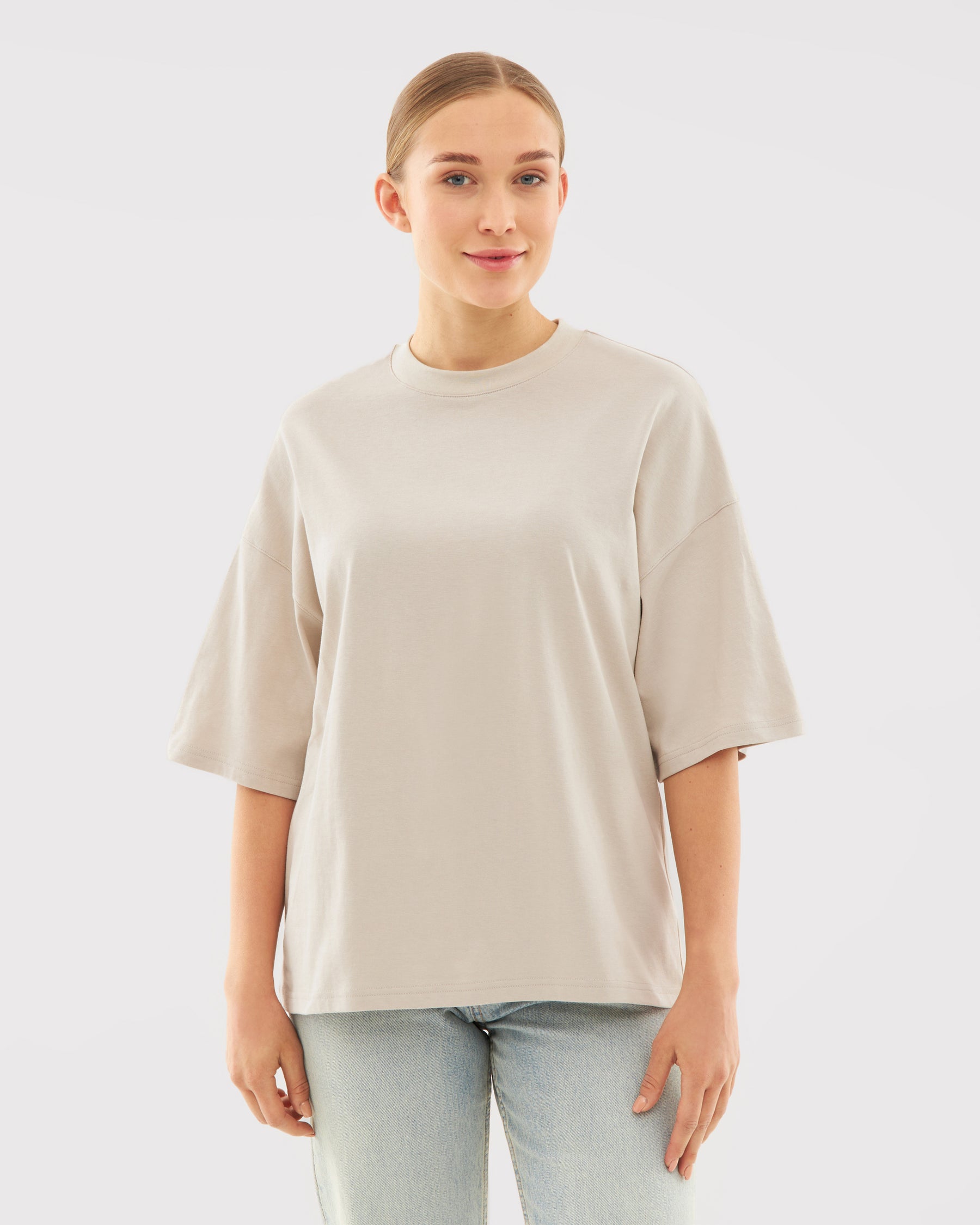 Beige T-Shirt 'Vic' mit kurzem, weitem Schnitt, getragen von Frau mit zusammengebundenen Haaren