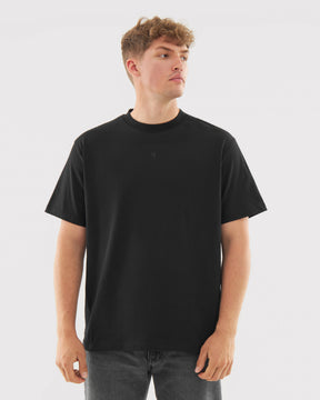 Mann trägt schwarzes Oversize-T-Shirt 'Sammy Butterfly' mit kleinem Logo vorn