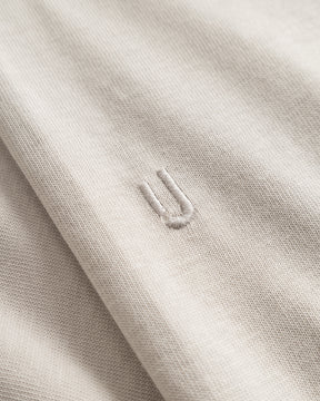 Nahaufnahme des beigen Stoffs eines Oversize-T-Shirts 'Vic' mit eingesticktem Detail