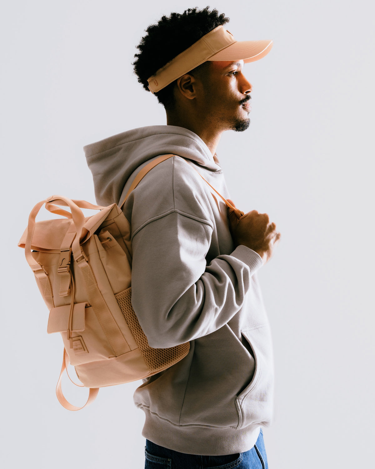 Mann in grauem Hoodie und Cap trägt peachfarbenen Tagesrucksack 'Jules' von Johnny Urban auf Schultern