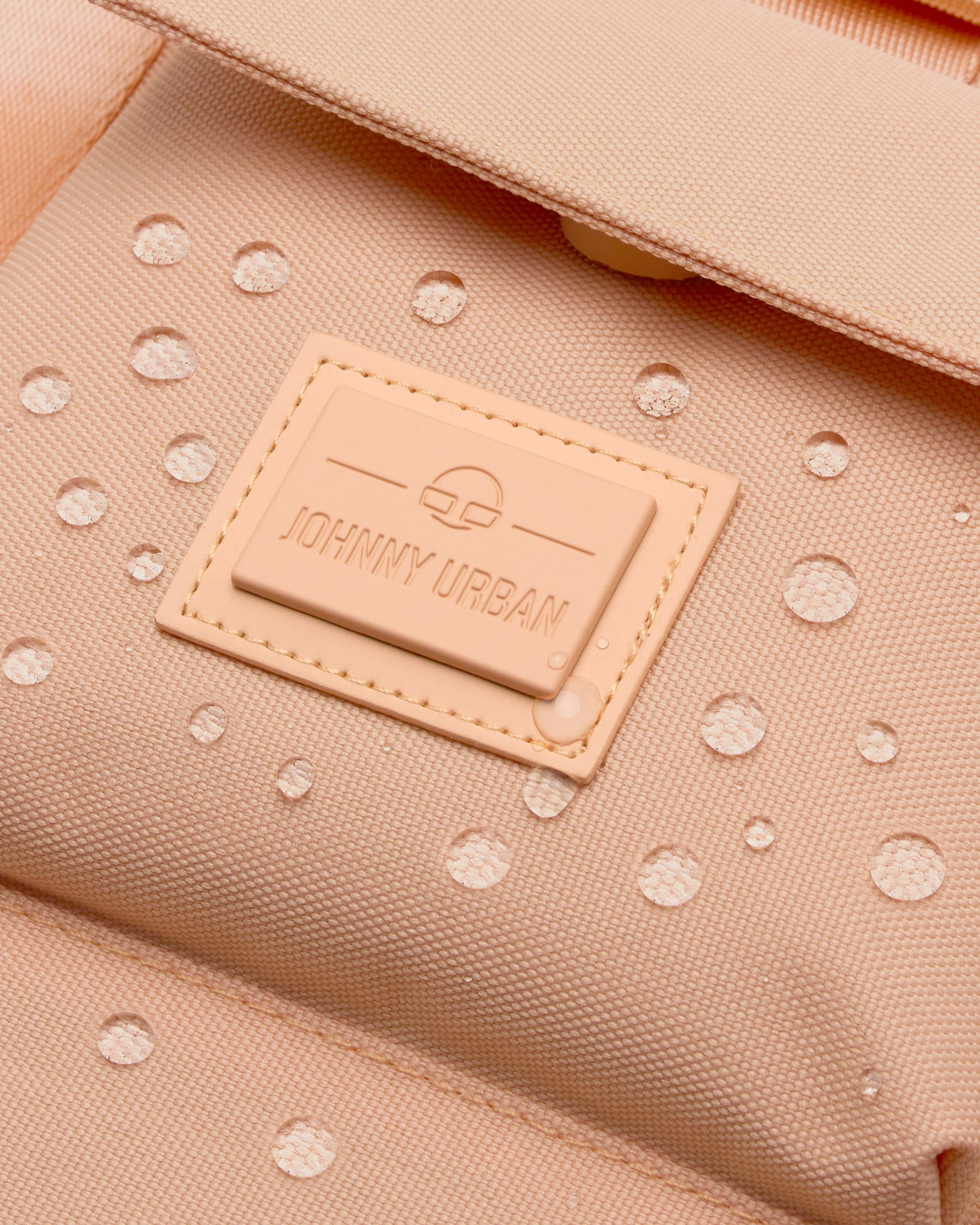 Nahaufnahme des peachfarbenen, wasserabweisenden Rucksacks 'Jules' von Johnny Urban mit Logo-Patch