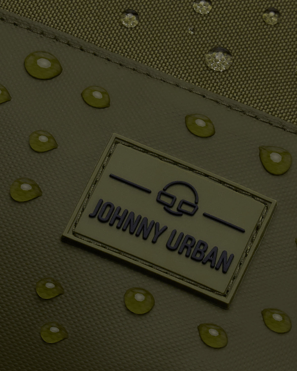 Nahaufnahme des wasserabweisenden, olivfarbenen Rucksacks 'Mika' von Johnny Urban mit Markenlogo und Wassertropfen