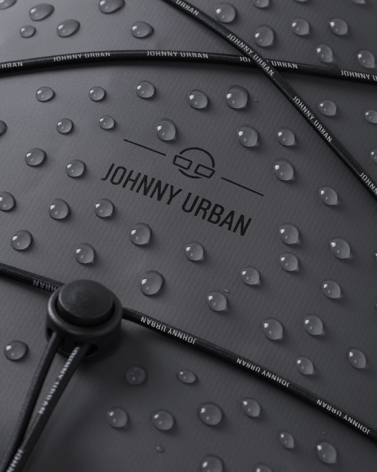 Wasserabweisende Oberfläche des grauen Rolltop Rucksacks 'Myles' von Johnny Urban mit Wassertropfen und verstellbarem Kordelzug