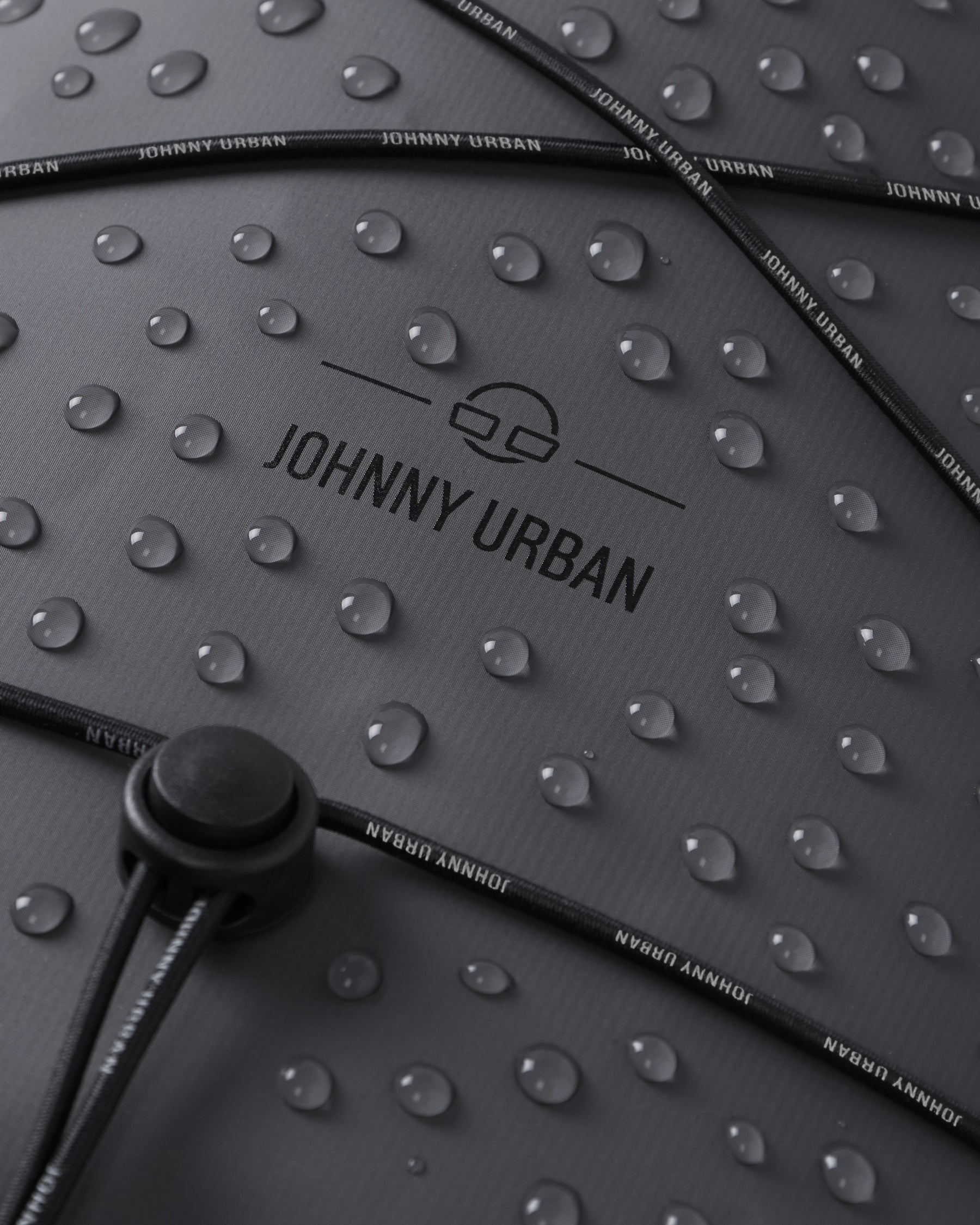Wasserabweisende Oberfläche des grauen Rolltop Rucksacks 'Myles' von Johnny Urban mit Wassertropfen und verstellbarem Kordelzug