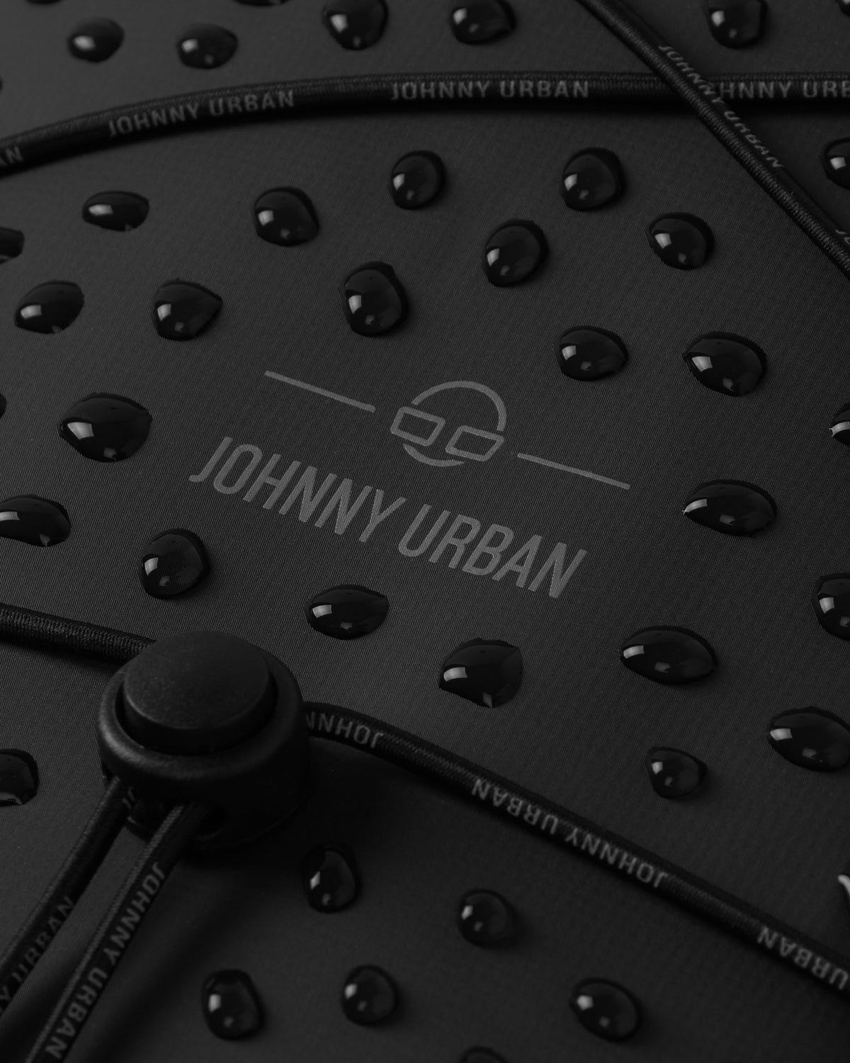 Wasserabweisende Oberfläche eines schwarzen Johnny Urban Rolltop Rucksacks 'Myles' mit Wassertropfen