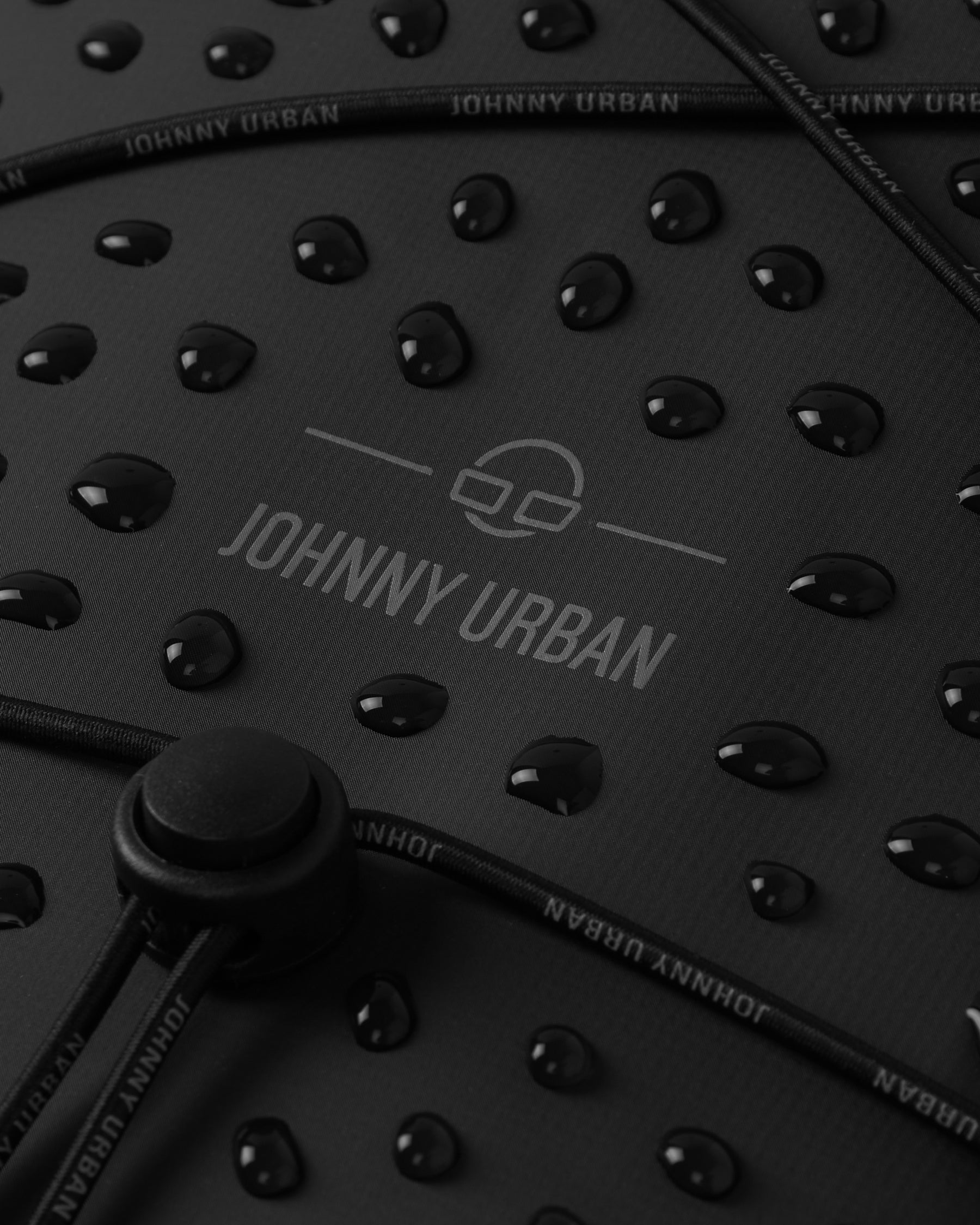 Wasserabweisende Oberfläche eines schwarzen Johnny Urban Rolltop Rucksacks 'Myles' mit Wassertropfen