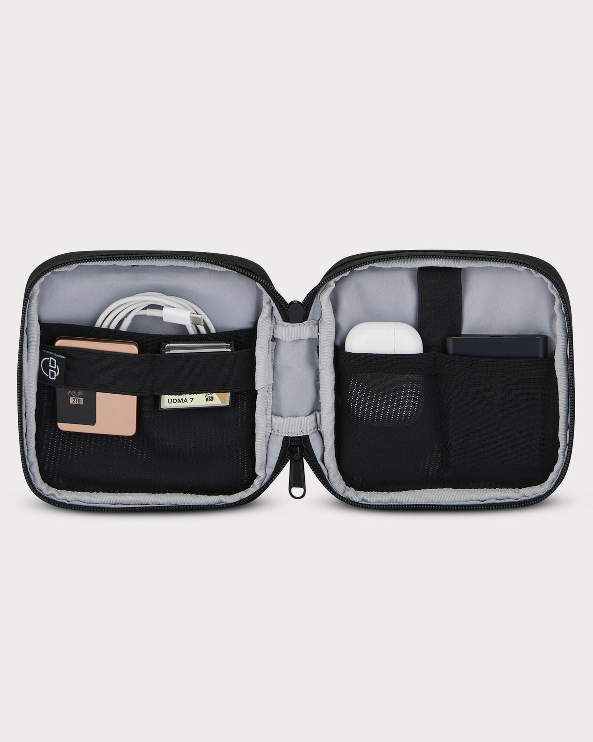 Geöffneter schwarzer Tech Organizer 'Ted' mit mehreren Taschen, gefüllt mit Kabel, Speicherkarte, AirPods und externem Akku