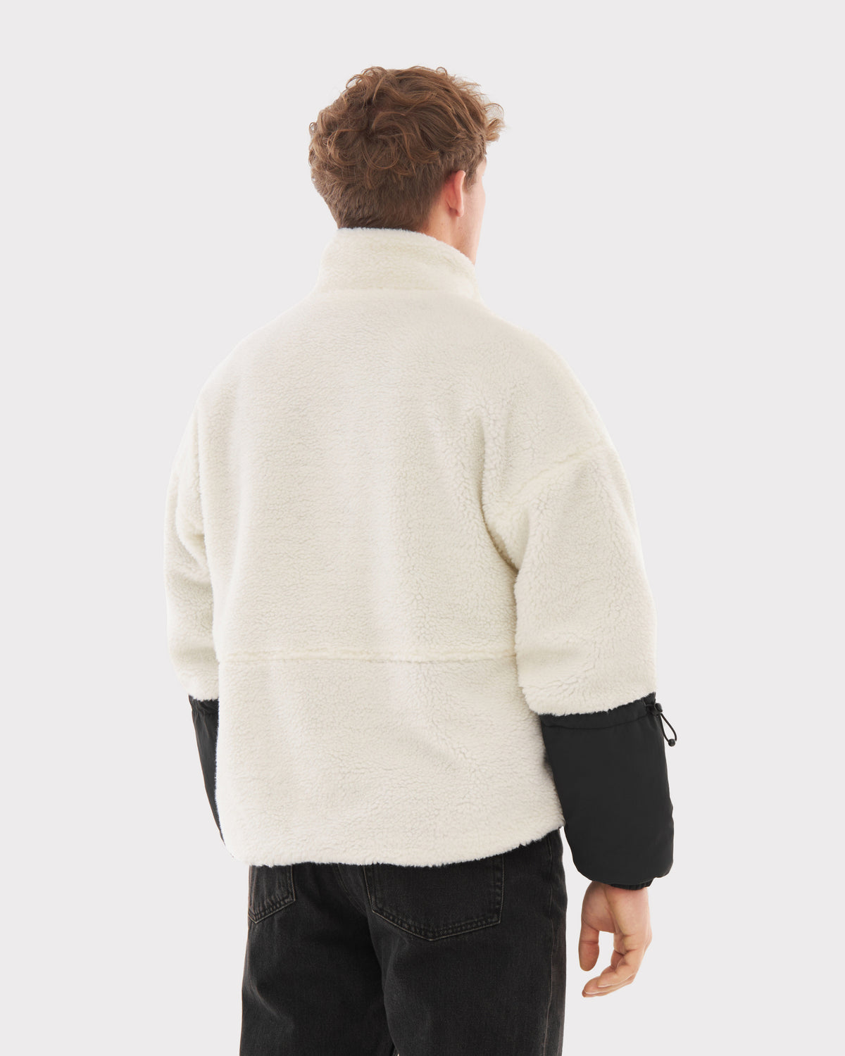 Rückansicht einer Person mit Teddy Fleecejacke 'Carson' in Creme und schwarzen Ärmeln