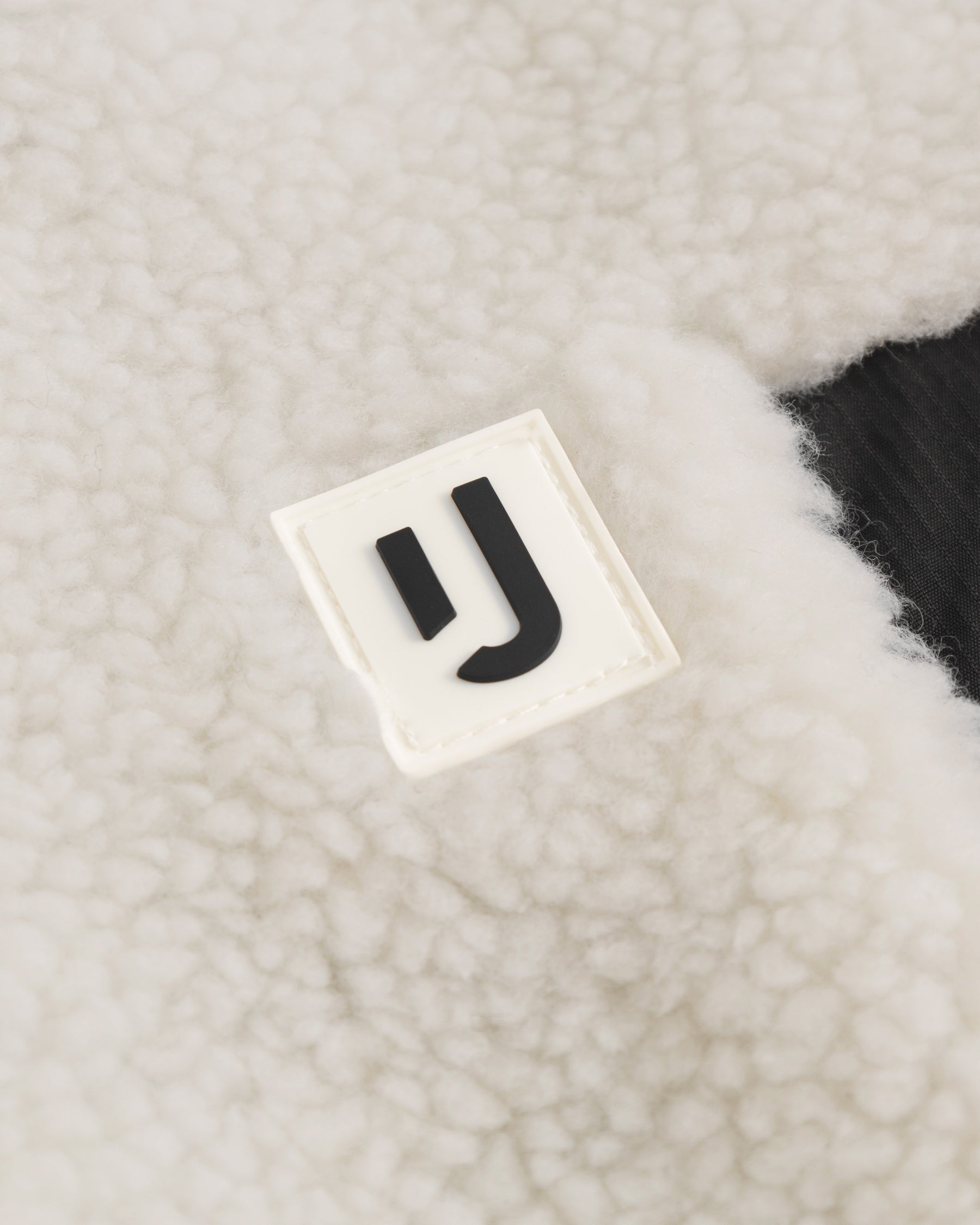 Nahe Aufnahme des weißen Teddy-Fleece-Stoffs der Fleecejacke "Carson" mit Johnny Urban Logo
