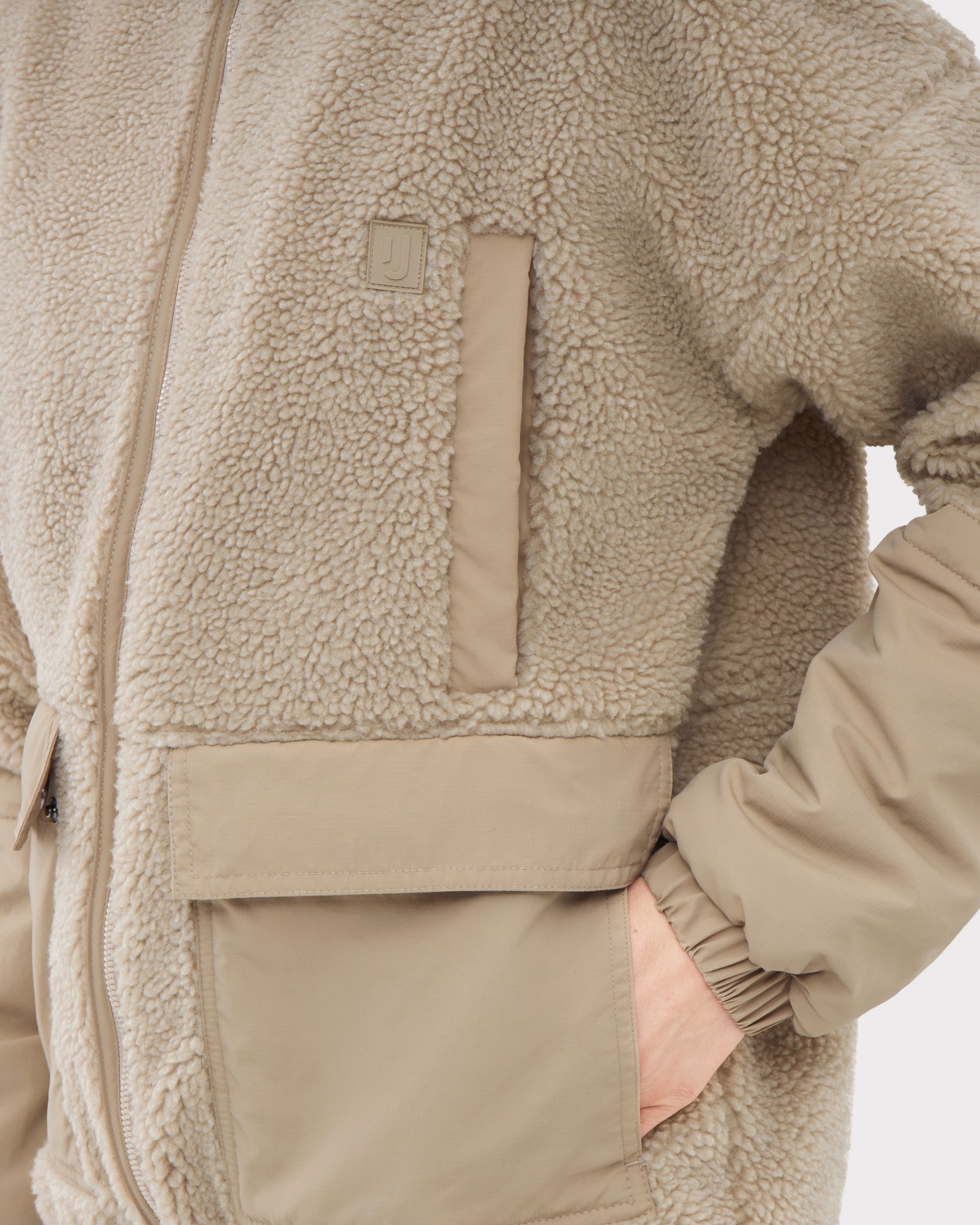 Beige Teddy Fleecejacke 'Carson' mit kuscheligem Obermaterial und glatten Ärmelabschnitten, eine Hand in der Tasche