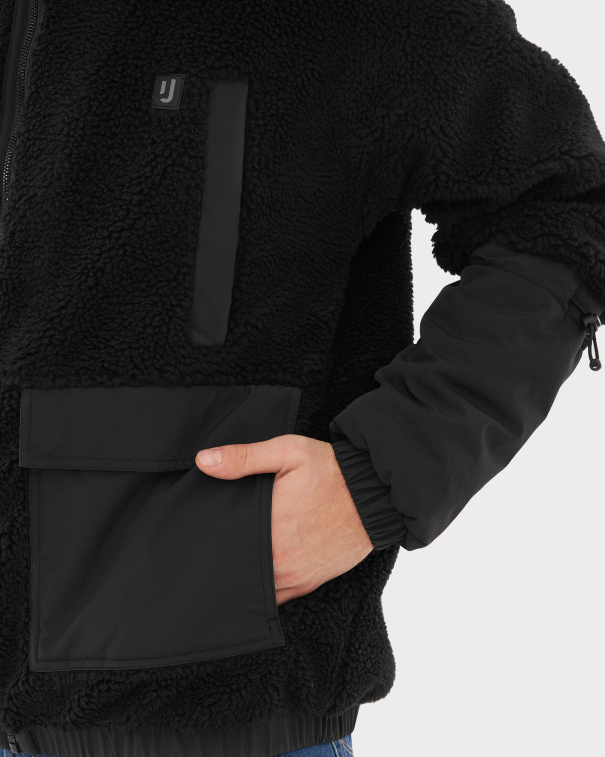 Schwarze Teddy Fleecejacke 'Carson' mit Reißverschluss, zwei Taschen vorne, eine Hand in der Tasche