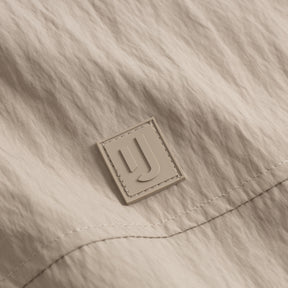 Nahe Aufnahme des Logos auf der beigen Übergangsjacke 'Lennon' von Johnny Urban