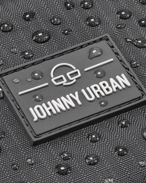Nahaufnahme des Johnny Urban Logos auf grauem, wasserabweisendem Stoff mit Wassertropfen
