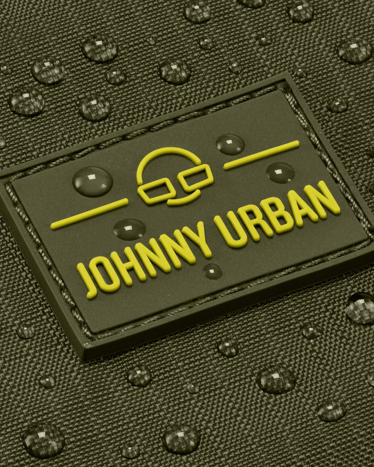 Nahaufnahme der wasserabweisenden Oberfläche und des gelben Johnny Urban Logos auf olivgrüner Umhängetasche 'Jayden'