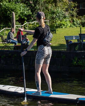 Frau auf Paddleboard mit schwarzer Lenkertasche Fahrrad 'Arlo' am Körper beim Paddeln
