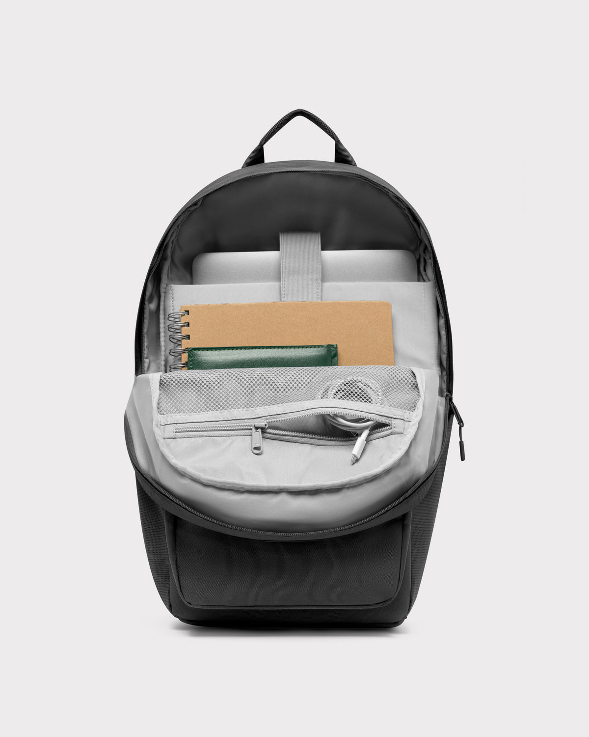 Schwarzer Rucksack 'Mo' von Johnny Urban mit Laptopfach, Notizbuch, grünem Portemonnaie und Kopfhörerkabel im Innenfach