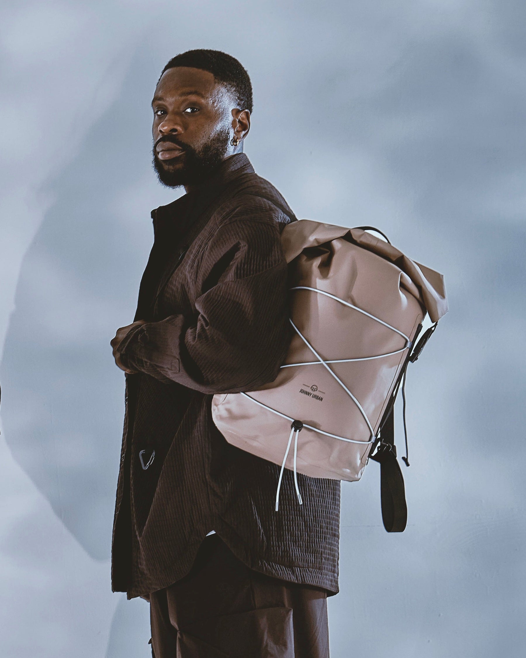 Frau und Mann tragen jeweils einen braunen Rolltop-Rucksack 'Myles' von Johnny Urban