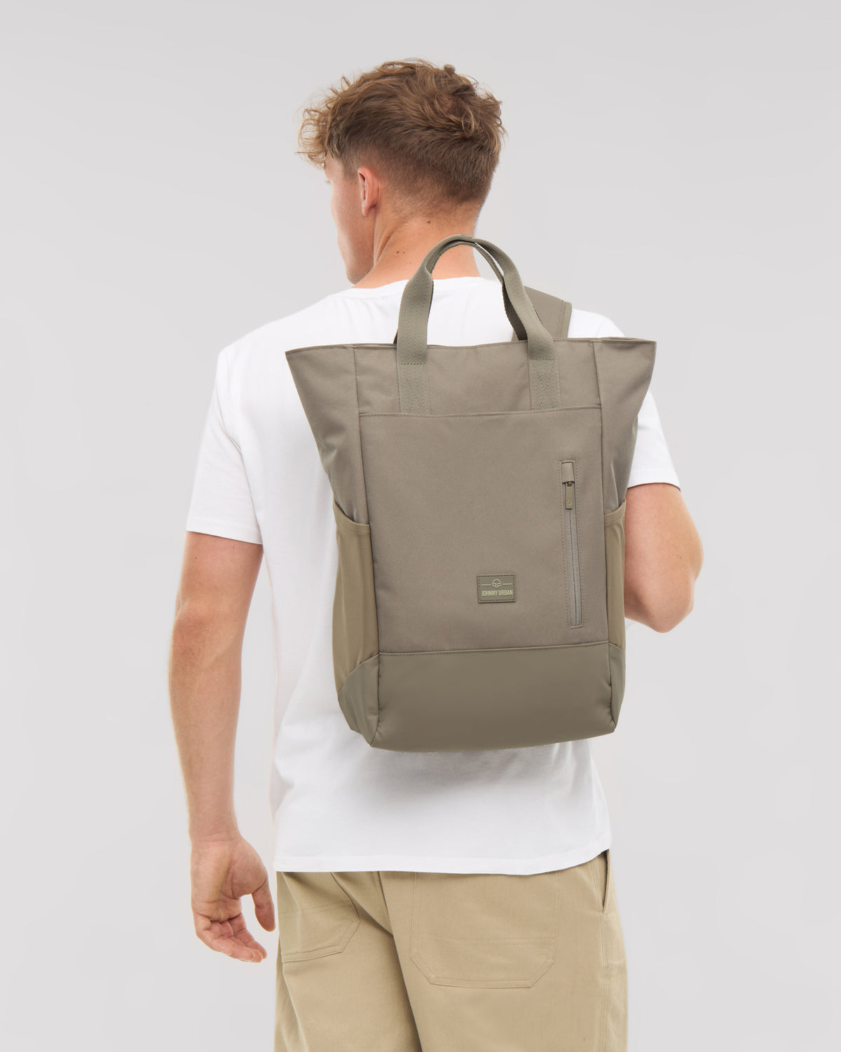 Mann von hinten mit Wickeltasche 'Blair' in Desert Grey, Trageträger und Griffe sichtbar