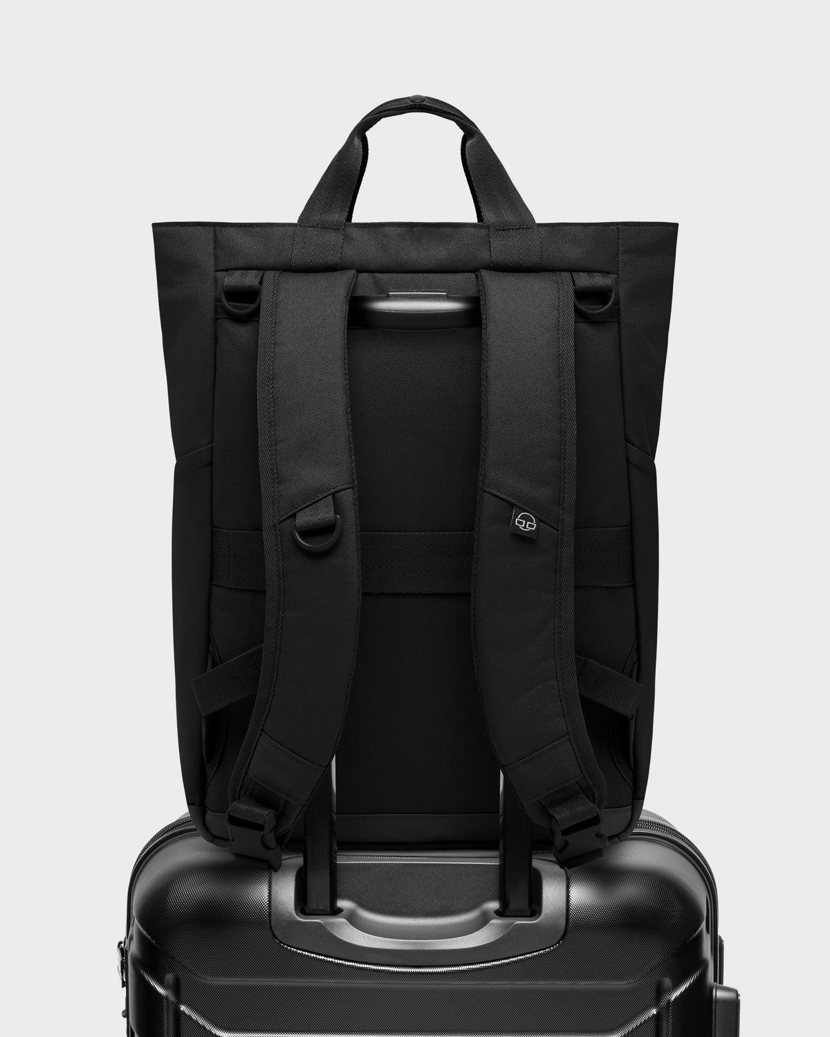 Wickeltasche 'Blair' als Rucksack auf schwarzem Hartschalenkoffer mit Ausziehaut am Griff