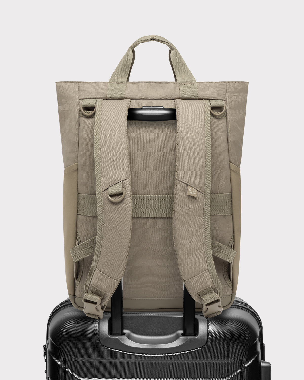 Rückansicht der Wickeltasche 'Blair' in Beige auf einem schwarzen Trolley-Koffer befestigt
